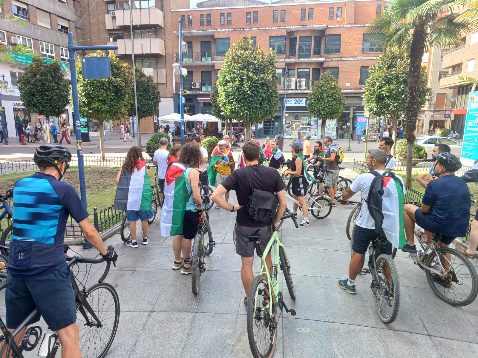 Fotografía de gran parte de les ciclistas que participan en la bicicletada. Casi todes llevan banderas palestinas en la espalda.